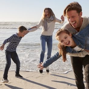 Parents With Children Having Fun On Winter Beach Together