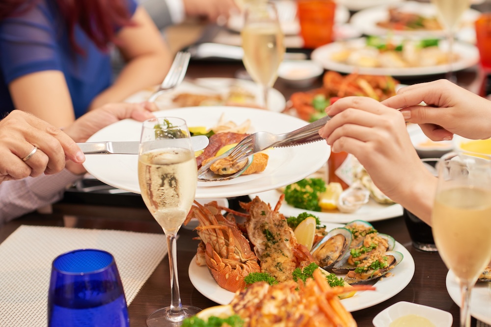 Hands of woman putting shellfish mussels to the plate of her husband at festive dinner 