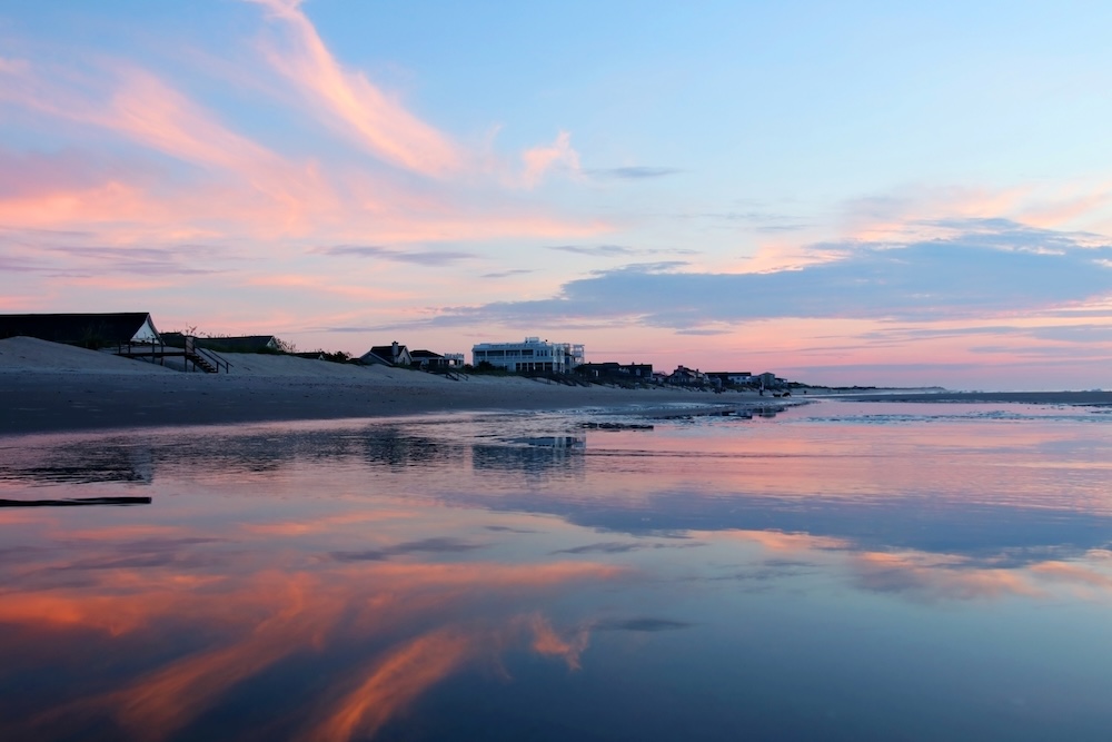 Marine background with beautiful colorful sky reflects in a shallow water during low tide before sunrise. Scenic seascape at the Pawleys Island, South Carolina, USA.
